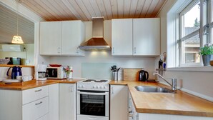 A compact kitchen with white cabinets, a stove, a sink, and a window. - "Swaver" - 300m to the fjord by Interhome (Storvorde)