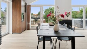 Un comedor moderno con una mesa grande, sillas y un jarrón de flores.