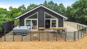 Una casa moderna con terraza, jacuzzi y un patio cubierto.