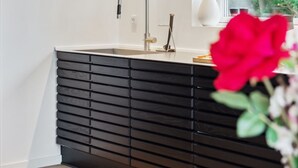 Una cocina moderna con una encimera negra elegante, un grifo de acero inoxidable y un ventanal con vistas a zonas verdes.