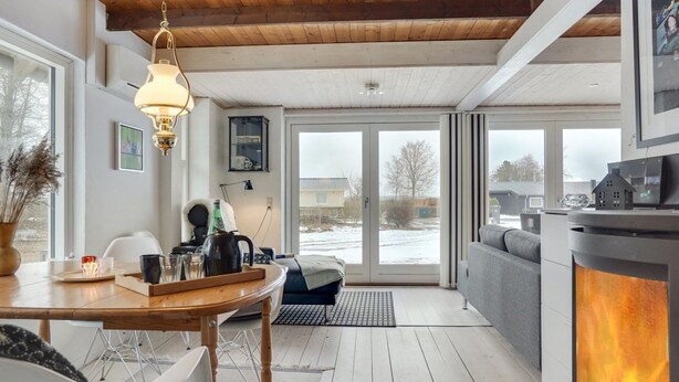 Una sala de estar moderna con chimenea, techo de madera y ventanas amplias.