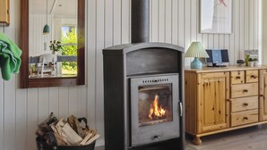 Une pièce chaleureuse avec un poêle à bois, des meubles en bois, un miroir et une affiche encadrée accrochée au mur.