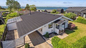Une maison moderne avec un toit plat, des panneaux solaires et une vue sur la mer.