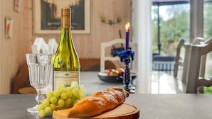 Une table avec une bouteille de vin, un verre, des raisins et un croissant.