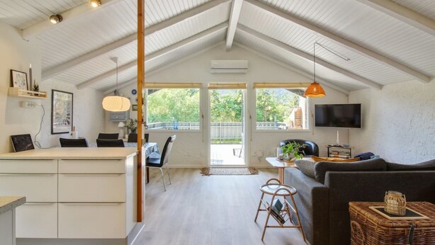 A spacious living area with a high ceiling, a kitchen area with a counter and chairs, a sofa, a television, and a wicker basket. - "Weland" - 800m from the sea by Interhome (Løkken)