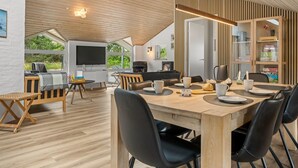 Un interior moderno con comedor, chimenea y televisor.