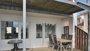 A covered patio area with a table and chairs, a wooden deck, and a view of the surrounding neighborhood. - "Haghni" - 200m from the sea by Interhome (Løkken)