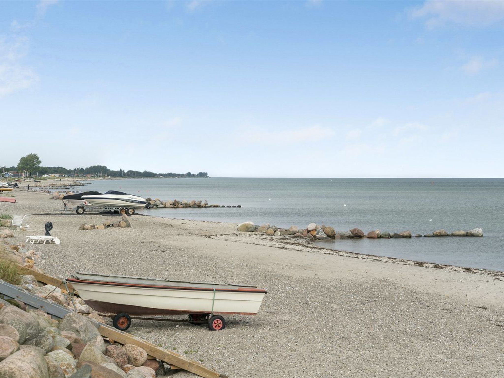 En strand med grus, både og en trailer.