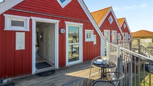 A row of red wooden houses with white trim, each featuring a door and windows, and a wooden deck with outdoor seating. - "Poulsen" - 200m from the sea by Interhome (Løkken)
