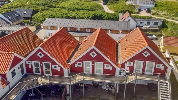 A coastal building complex with multiple red-roofed houses, a white tower, and a view of the sea. - "Poulsen" - 200m from the sea by Interhome (Løkken)