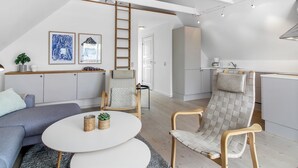 A modern loft apartment with a high ceiling, exposed beams, a kitchen area, and a living space with a sofa and armchairs. - "Poulsen" - 200m from the sea by Interhome (Løkken)