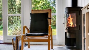 A room with a large window, a wooden chair, and a wood-burning stove. - "Gottfrede" - 600m from the sea by Interhome (Løkken)
