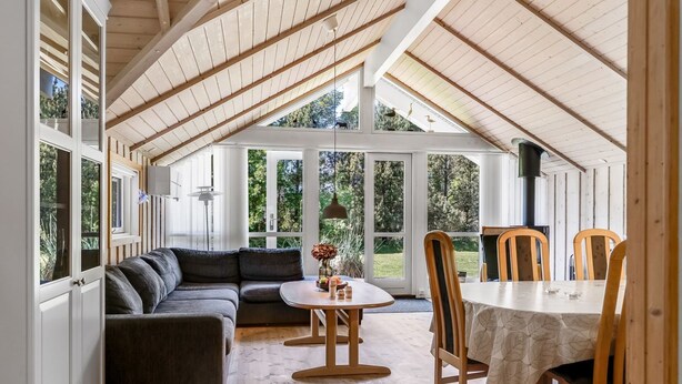 An open-plan living and dining area with a high ceiling, wooden beams, and large windows offering views of the outdoors. - "Gottfrede" - 600m from the sea by Interhome (Løkken)