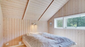 A bedroom with a bed, wooden walls, a window, and a wall-mounted light fixture. - "Gottfrede" - 600m from the sea by Interhome (Løkken)