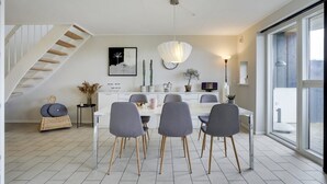 Une cuisine moderne avec un coin repas, comprenant un escalier, des meubles blancs et une grande fenêtre.