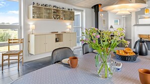 Uma área de jantar moderna com uma mesa hexagonal, um vaso de flores e uma cesta de pão.