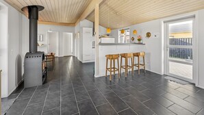 Cozinha moderna com azulejos escuros, vigas de madeira no teto e fogão preto.