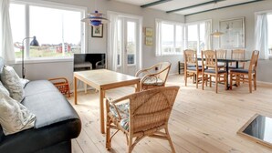 Un vaste espace de vie comprenant un canapé, une table à manger, des chaises et un téléviseur.