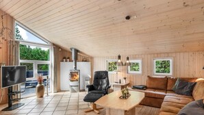 A cozy cabin interior with a fireplace, leather furniture, and large windows offering views of greenery. - "Tule" - 1.2km from the sea by Interhome (Blåvand)