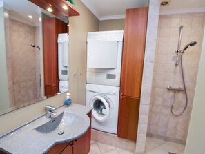 Ein Badezimmer mit Waschbecken, Waschmaschine und Dusche.
