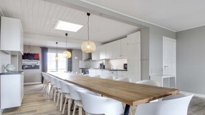 Eine moderne Küche mit weißen Schränken, einer Holztischinsel und Pendelleuchten.