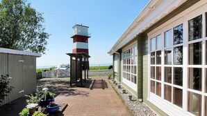 Ein Weg führt zu einem Leuchtturm, einem Gebäude mit großen Fenstern, und Blumentöpfen.