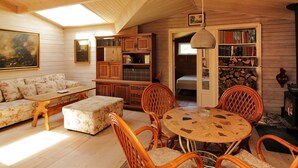A cozy, well-lit room with wooden walls, a sofa, a coffee table, wicker chairs, a bookshelf, and a fireplace. - "Enrik" - 123m from the sea by Interhome (Vordingborg)