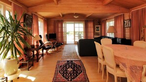 A cozy wooden cabin interior with a dining area, sofas, a television, and a large window. - "Enrik" - 123m from the sea by Interhome (Vordingborg)