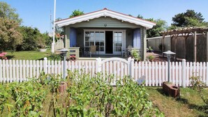 A single-story house with a front porch, a white picket fence, and a garden in the foreground. - "Enrik" - 123m from the sea by Interhome (Vordingborg)