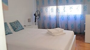 Um quarto com cama, ventilador e cortinas.