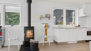 A modern kitchen with white cabinetry, a black stove, and a window overlooking greenery. - "Asla" - 400m from the sea by Interhome (Hals)