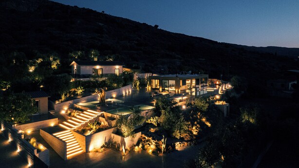 Ein luxuriöses Resort mit mehreren Schwimmbecken, einem gut beleuchteten Außenbereich und einer Bergkulisse.