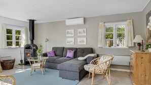 A cozy living room with a fireplace, grey sofa, wicker chairs, and a wooden cabinet. - "Ingobert" - 50m from the sea by Interhome (Hals)