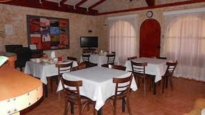 Un comedor con varias mesas y sillas, un televisor y un reloj en la pared.