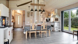Une cuisine moderne avec des poutres en bois, un coin repas avec une table et des chaises, et une grande fenêtre donnant sur l’extérieur.