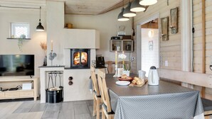 L’intérieur chaleureux d’un chalet avec une cheminée, des meubles en bois et une table à manger dressée pour deux personnes.