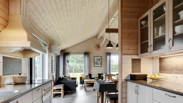 Une cuisine moderne avec un coin repas, un plafond en bois et de grandes fenêtres.