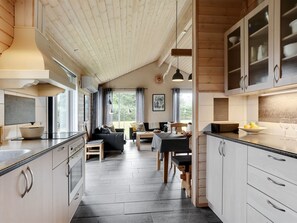 Eine moderne Küche mit Essbereich, Holzboden und großen Fenstern.