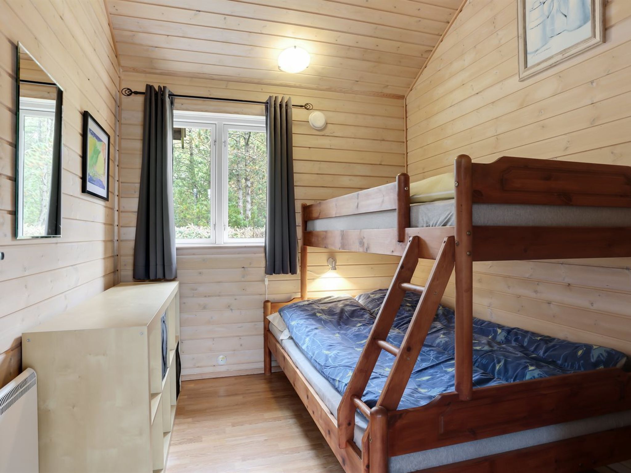 Une cabine comprenant un lit superposé, un bureau et une fenêtre avec des rideaux.