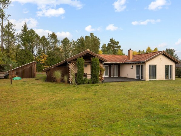Une maison de plain-pied avec un toit en pente, un porche à l’avant et un petit garage attenant.