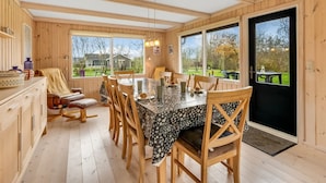 A wooden interior with a dining table, chairs, and a view through large windows. - "Scarlet" - 400m to the fjord by Interhome (Vinderup)