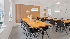 Ein moderner Essbereich mit einem langen Holztisch, schwarzen Stühlen und Pendelleuchten.