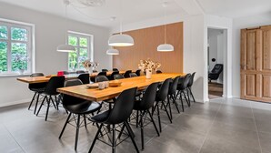 Ein stilvoller Essbereich mit einem langen Holztisch, schwarzen Stühlen und Pendelleuchten.