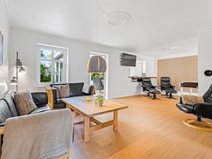 Un salon moderne comprenant un canapé, une table basse et des fauteuils, un téléviseur et un panneau mural en bois.