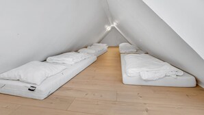Ein kleines, dreieckiges Schlafzimmer im Dachgeschoss mit zwei Einzelbetten und Holzboden.