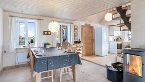 Een ruime keuken met een grote eettafel, een inbouwfornuis en uitzicht op de omgeving.