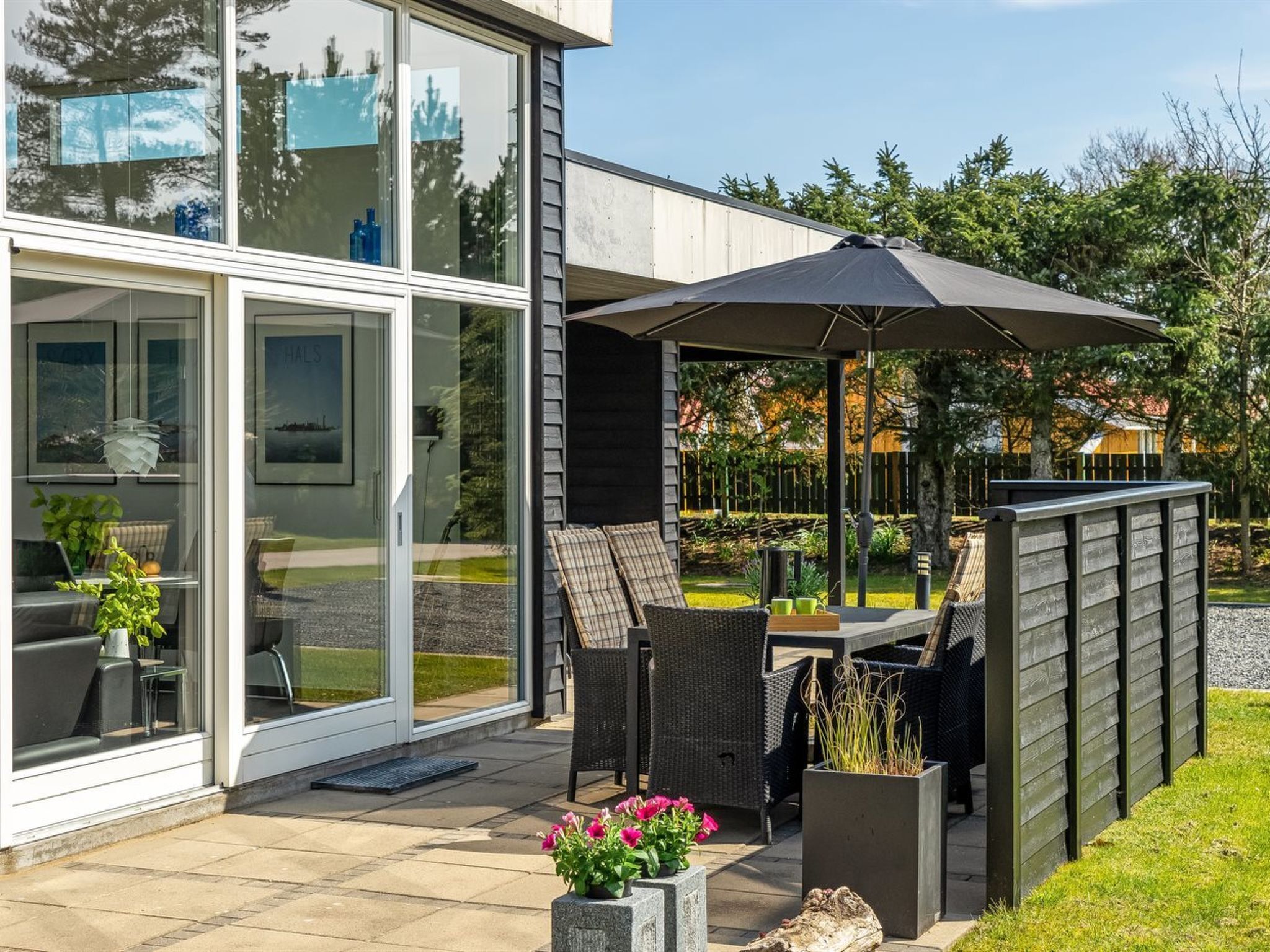 A modern patio with outdoor furniture and a large umbrella.