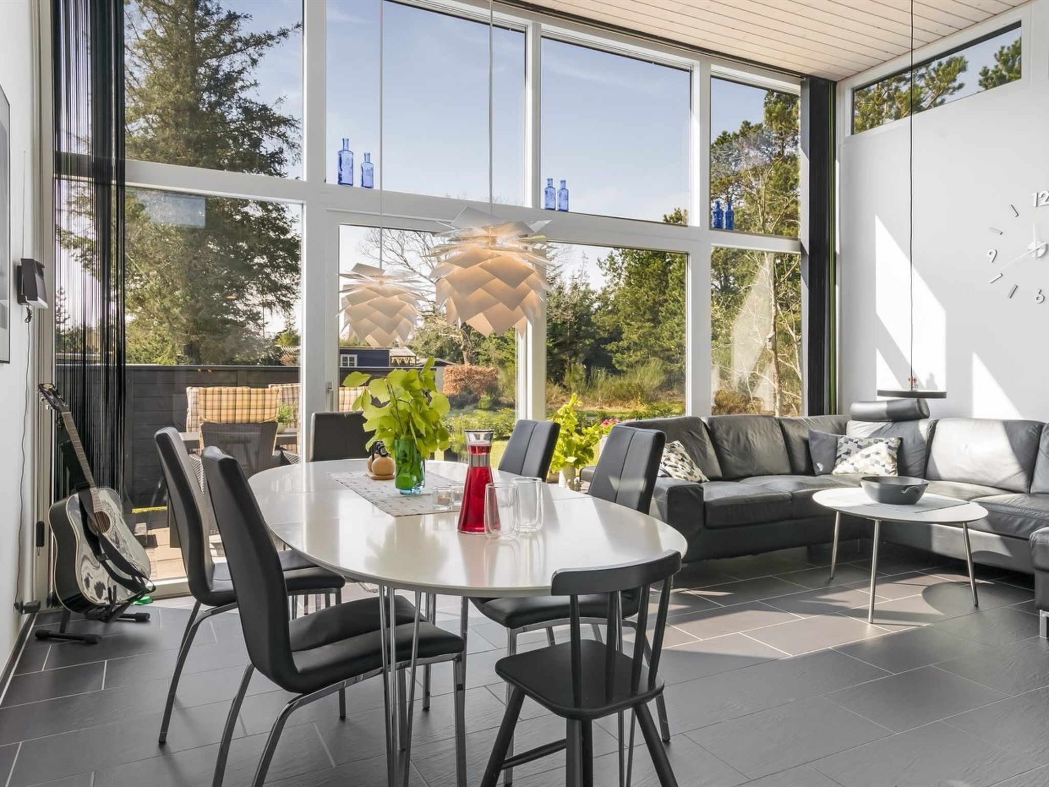 A modern living room with a dining area, large windows, and outdoor views.