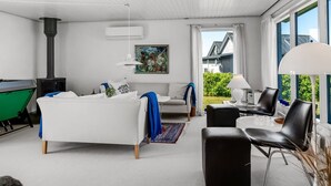 Ein modernes Wohnzimmer mit einem weißen Sofa, einem grünen Billardtisch, einem Kamin und einem Essbereich mit Tisch und Stühlen.