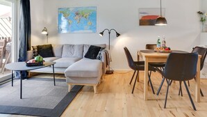 Uma sala de estar moderna com um sofá, uma mesa de jantar com cadeiras, um mapa-múndi na parede e um abajur.